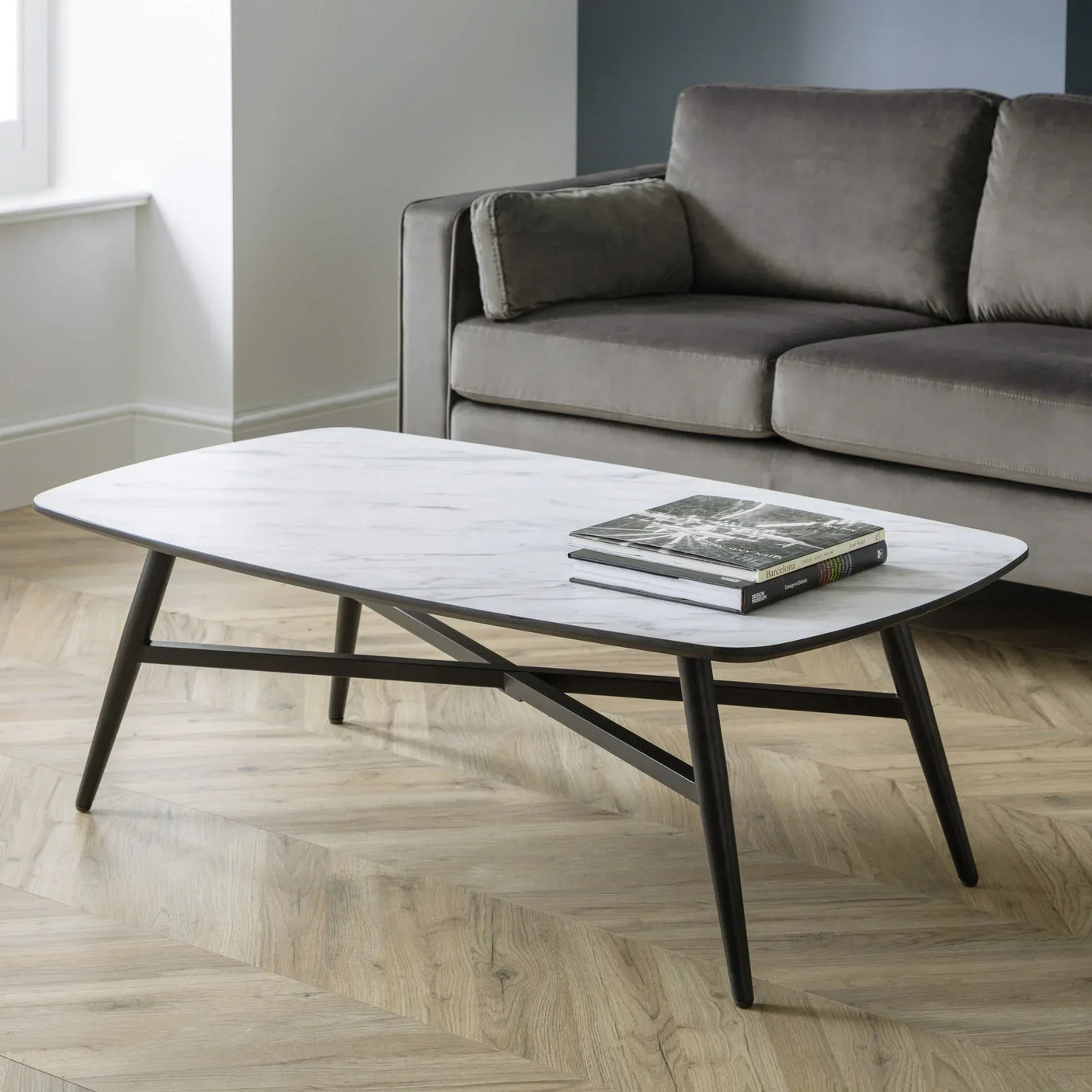 Marble coffee table with black legs in modern living room beside grey sofa