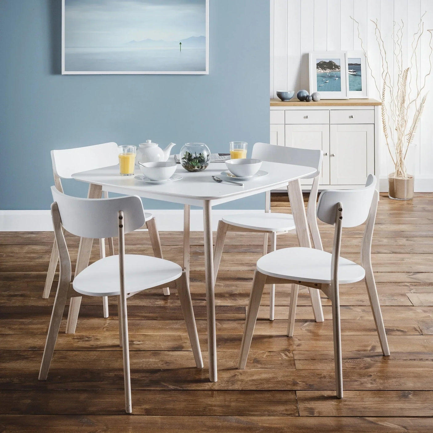 White dining room set with square table and four chairs on wooden floor