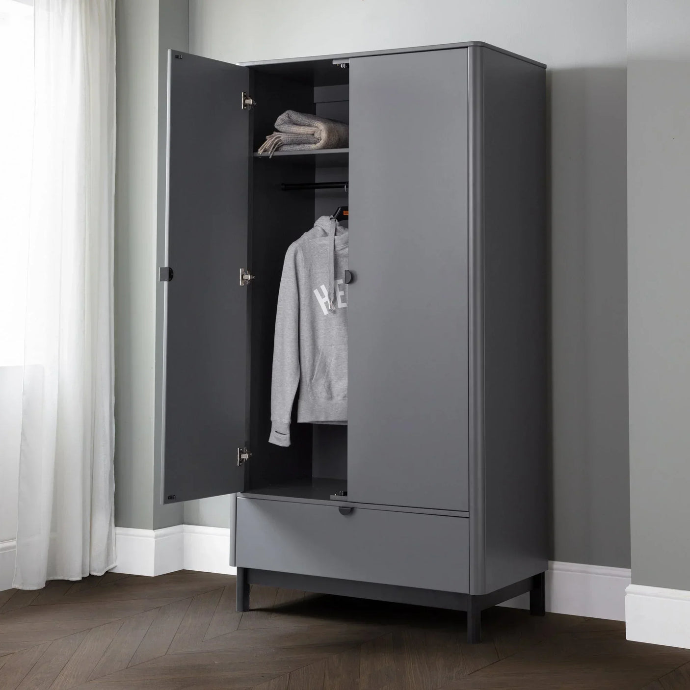 Grey wardrobe with open doors, shelving, hanging rail and lower drawer in modern room