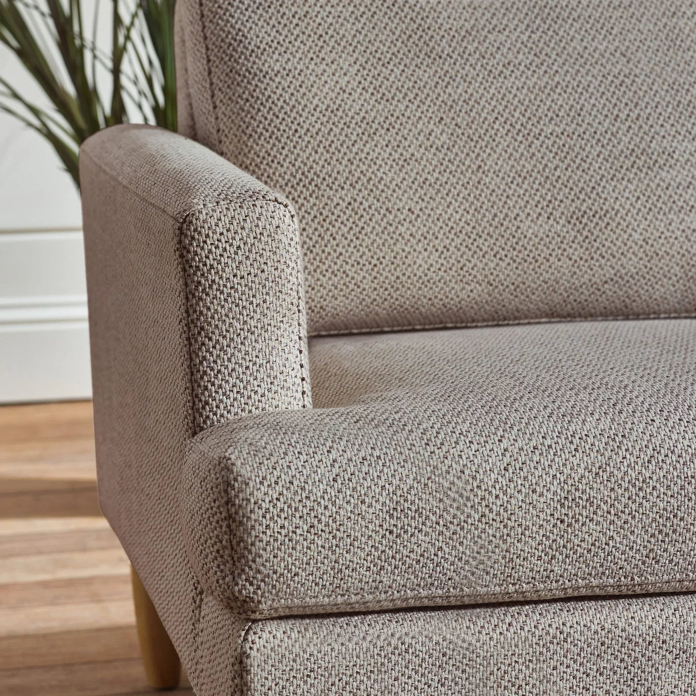 Close-up of beige fabric sofa armrest and seat with textured upholstery