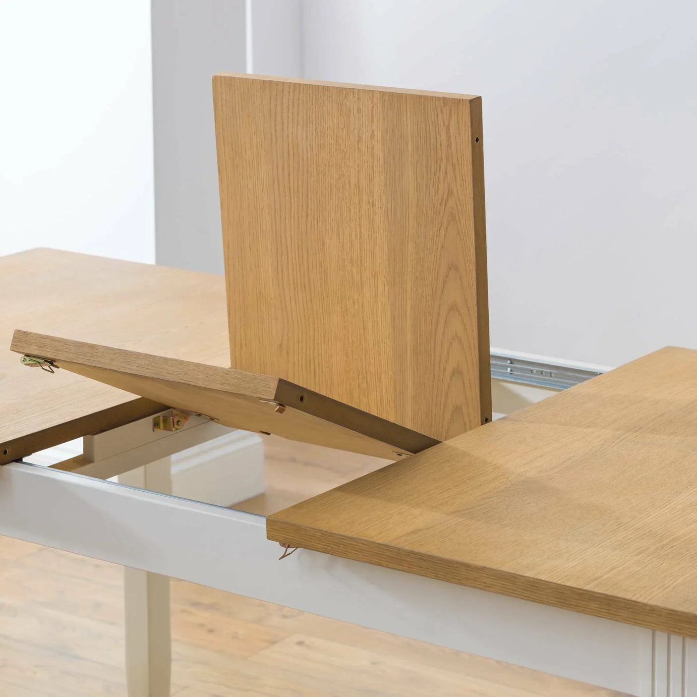 Oak extending dining table with folding leaf mechanism in mid-extension