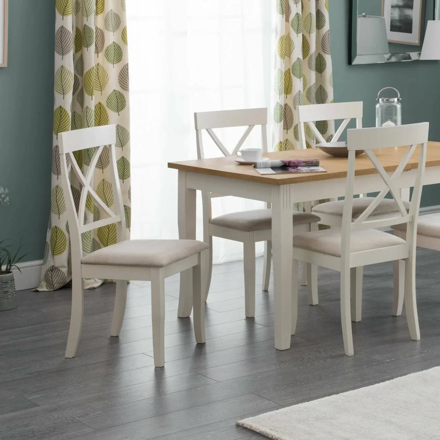 White extending dining table with wood top and four matching cross-back chairs in modern room
