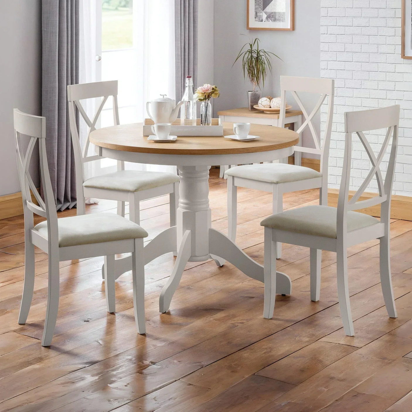 Round wood dining table with white chairs in bright dining room