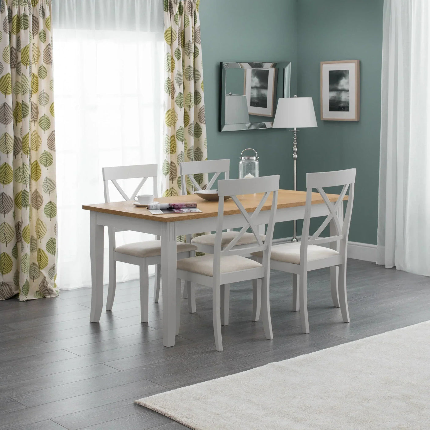 White wood dining table set with four chairs in a bright modern dining room