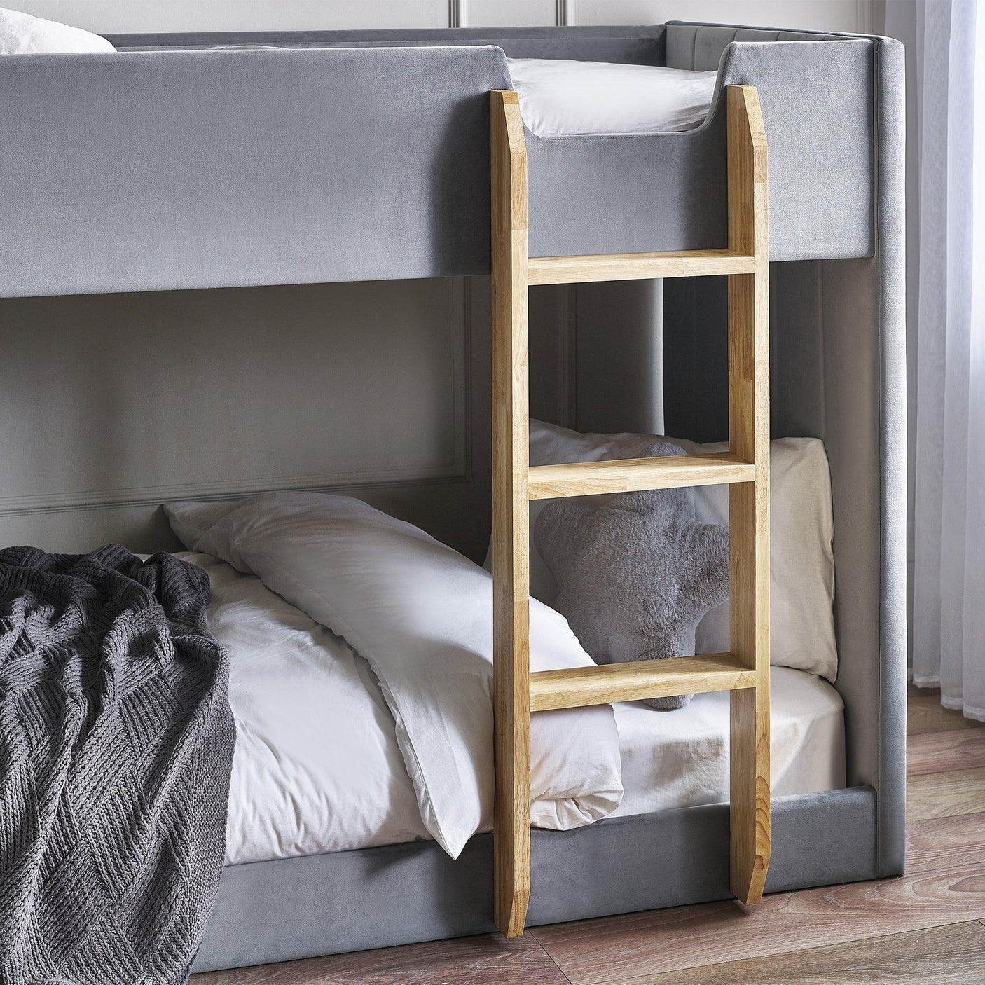 Grey fabric bunk bed with wooden ladder and white bedding in a modern bedroom