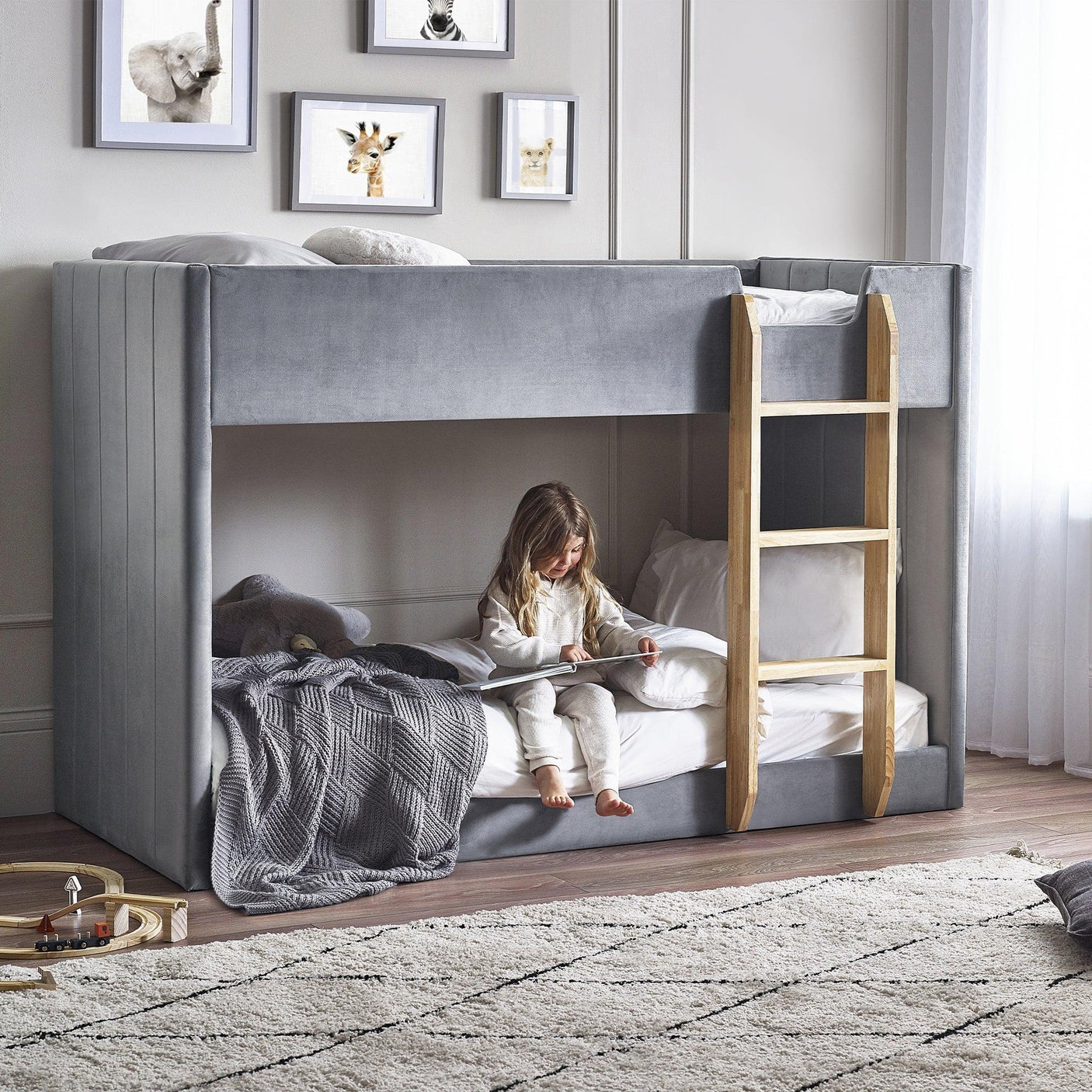 Grey fabric bunk bed with wood ladder in kids room, child reading on lower bunk