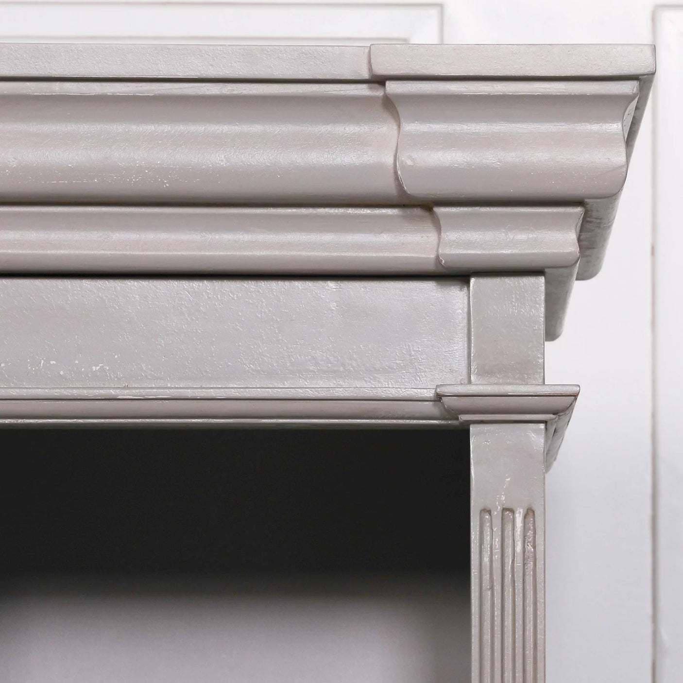 Grey painted wood fireplace mantel with detailed molding and fluted leg corner view
