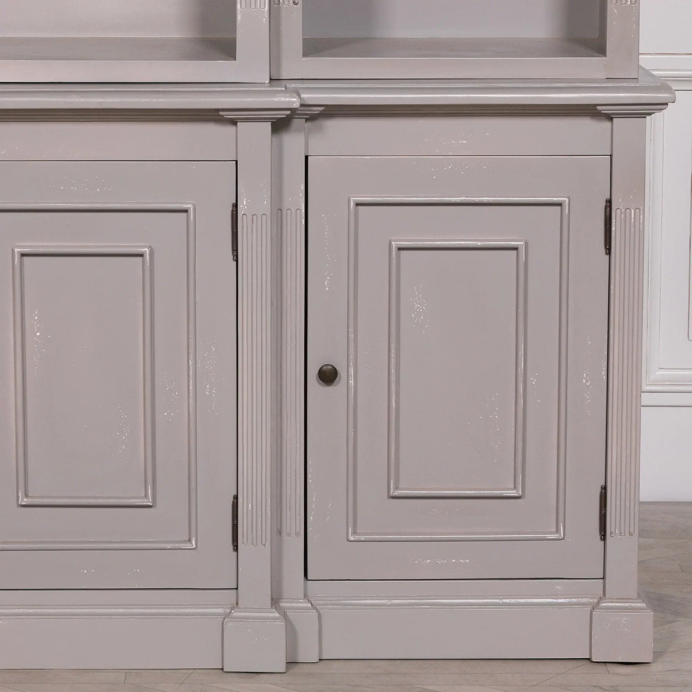 Close-up of grey wooden sideboard cabinet doors with panel detailing and brass knob