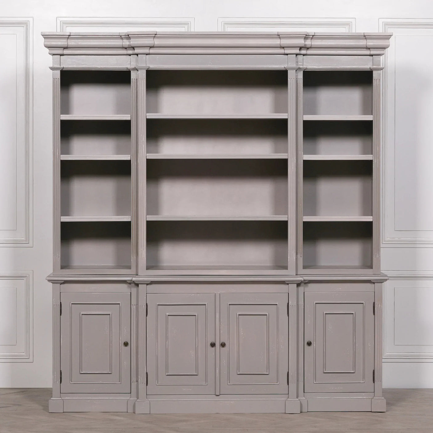 Grey wooden bookcase with open shelving and lower cabinets against a paneled wall