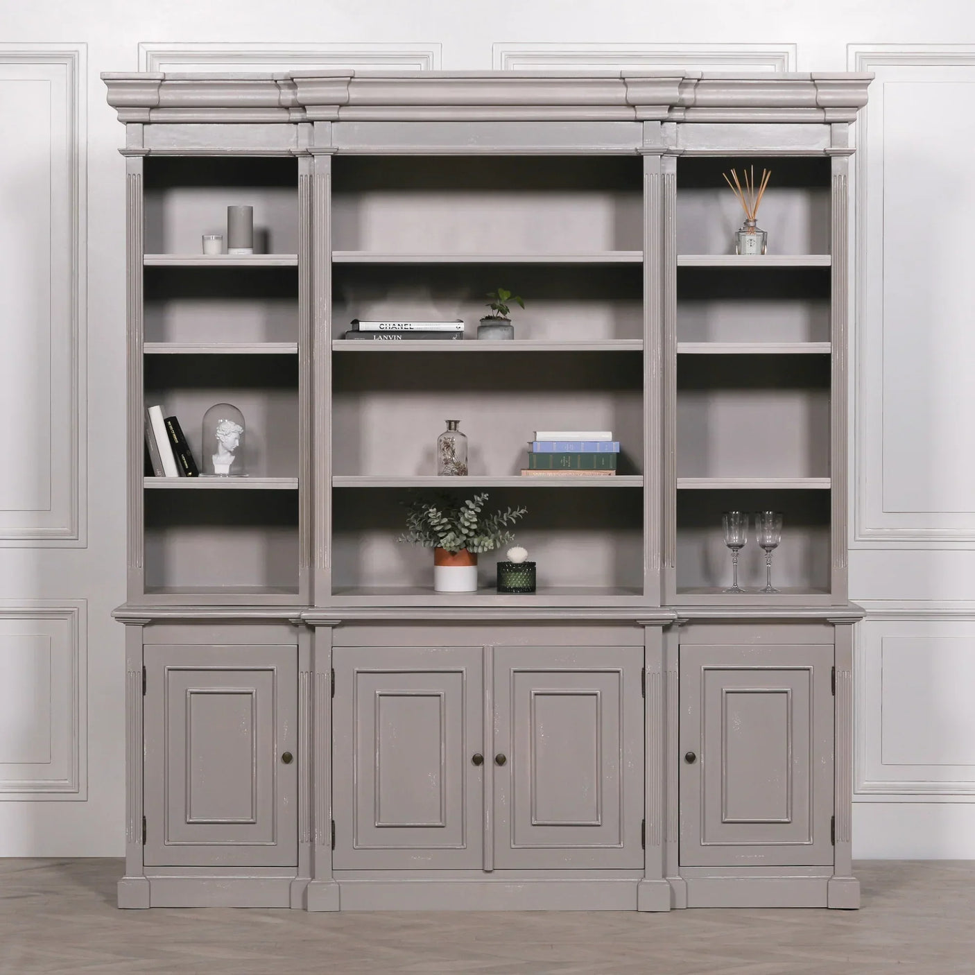 Grey wooden bookcase with open shelving and lower cabinets against white panel wall
