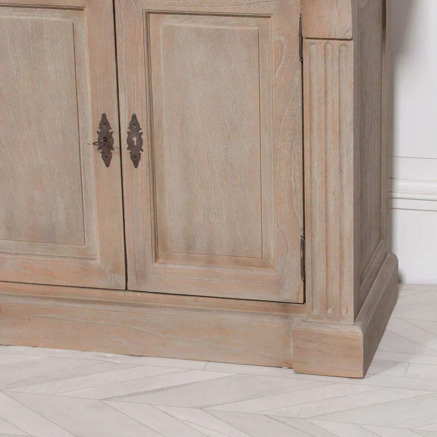 Light oak sideboard with ornate hardware and panelled doors on herringbone floor