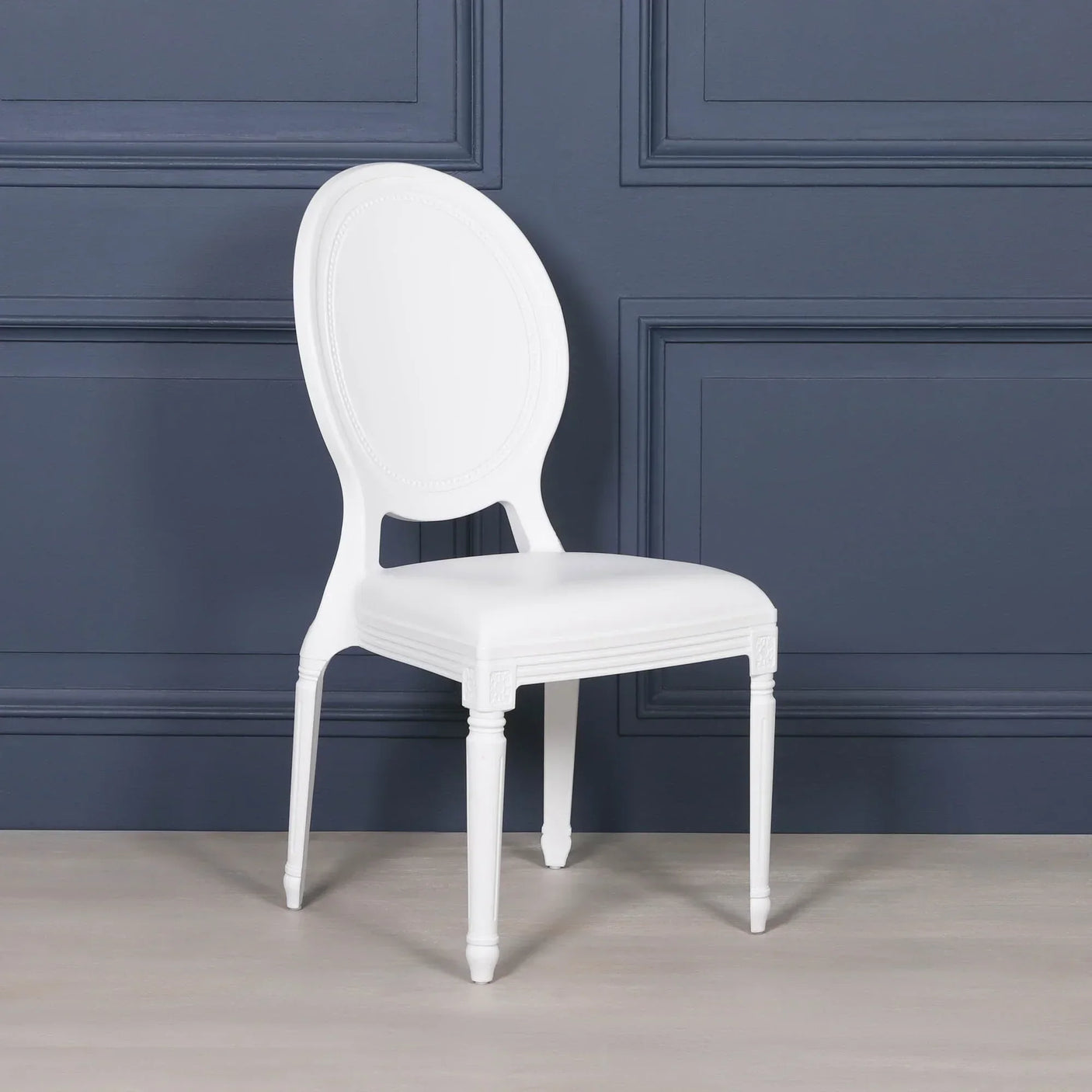 White dining chair with oval backrest and carved legs against dark wall