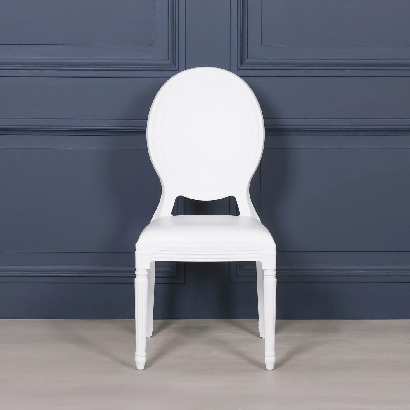 White dining chair with oval backrest and classic legs against dark blue wall