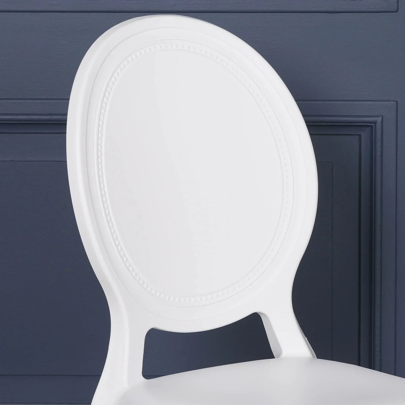 White dining chair with oval backrest and embossed edge detail against blue wall