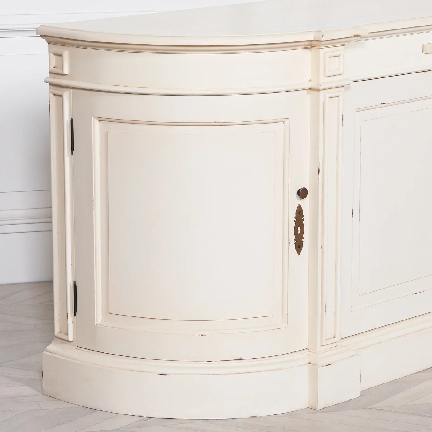 Cream painted wood sideboard corner with curved door and vintage-style keyplate