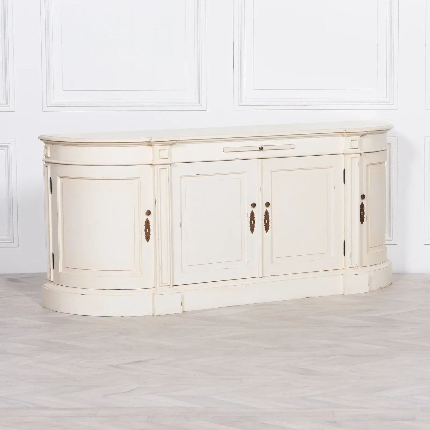Cream painted wooden sideboard with curved edges and brass handles in a bright room