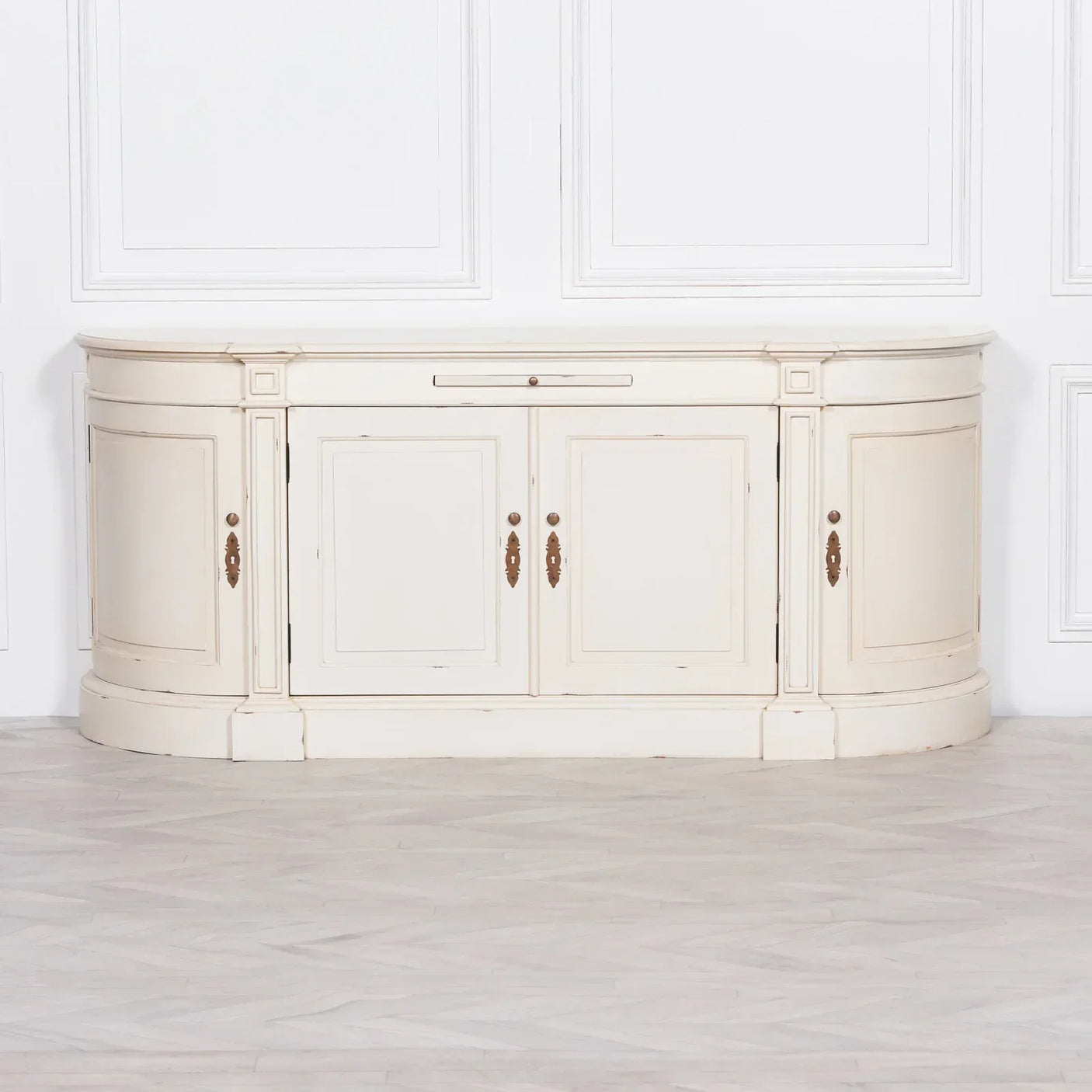 Cream painted sideboard with brass handles and paneled doors against white wall