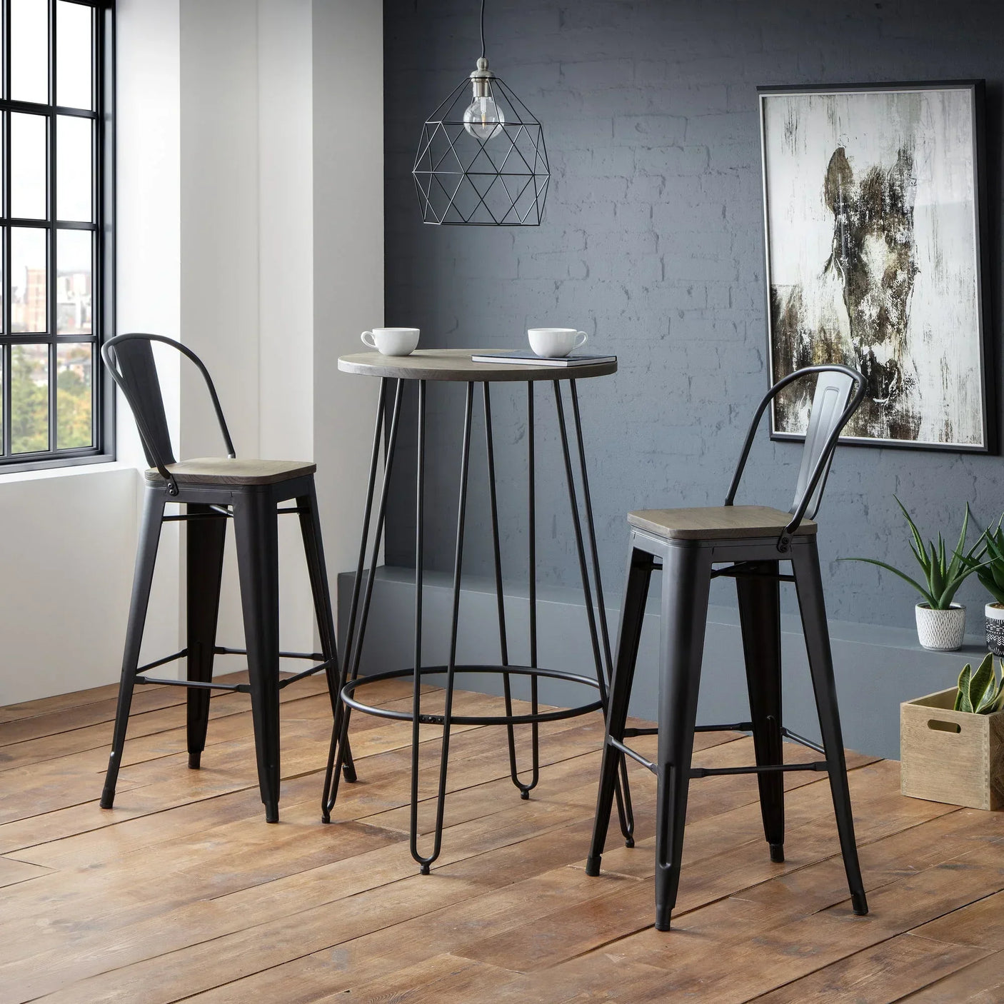 Industrial bar table and two metal bar stools with wood seats in modern dining area