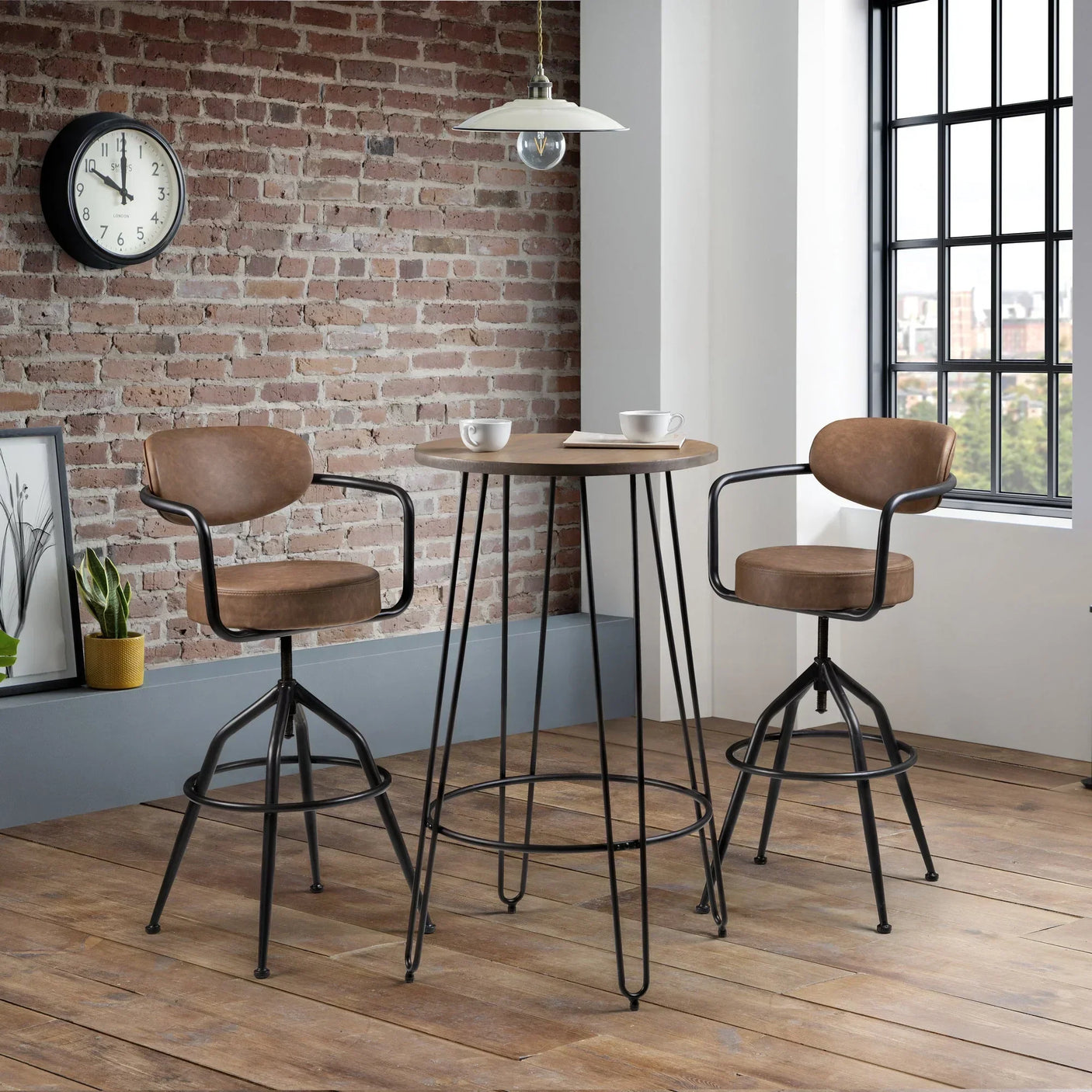 Industrial dining table with two brown bar stools in loft-style room with brick wall