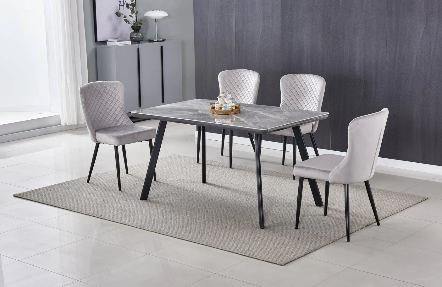 Rectangular marble dining table with black legs and four grey velvet chairs on a rug