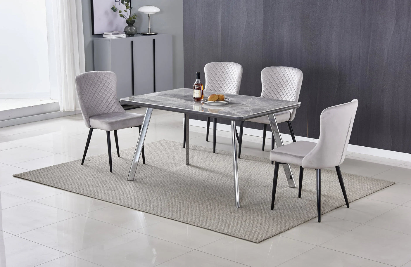 Modern dining table with chrome legs and grey velvet chairs on light rug