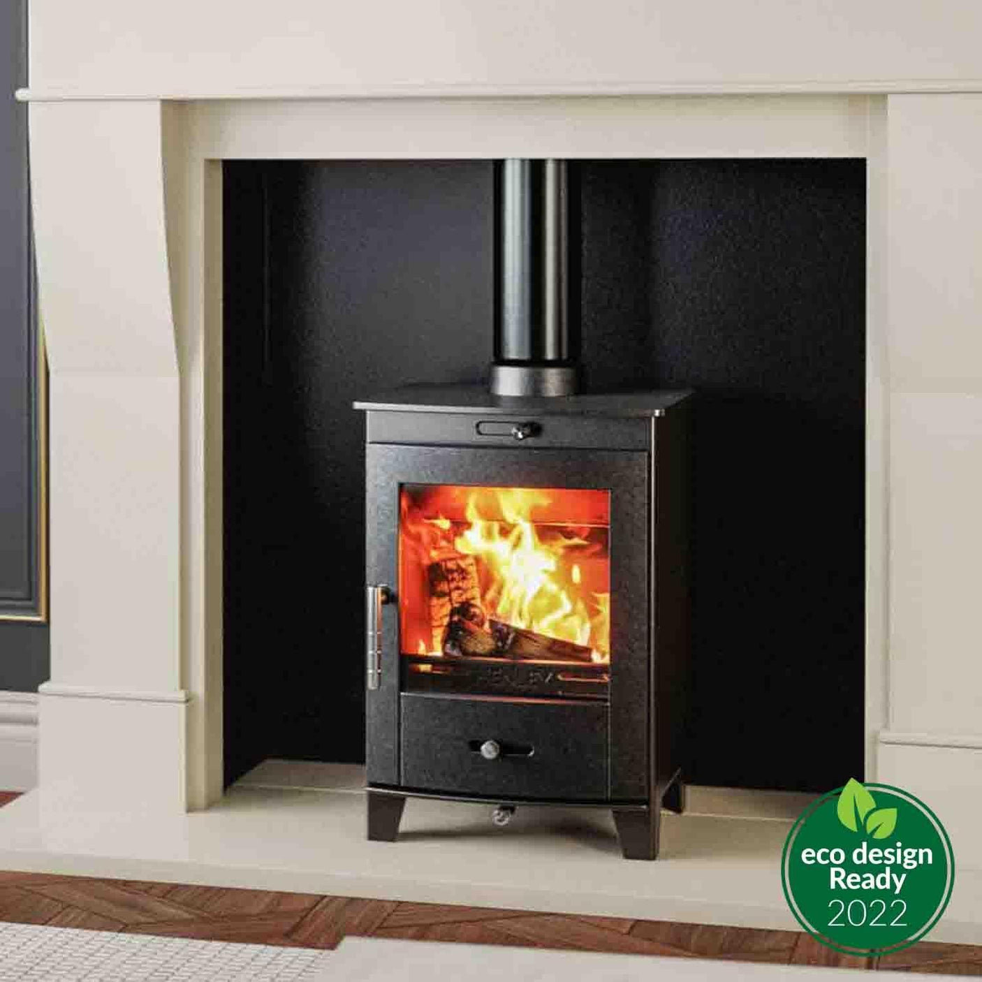 Black wood burning stove with glass door set in cream fireplace, eco design ready badge