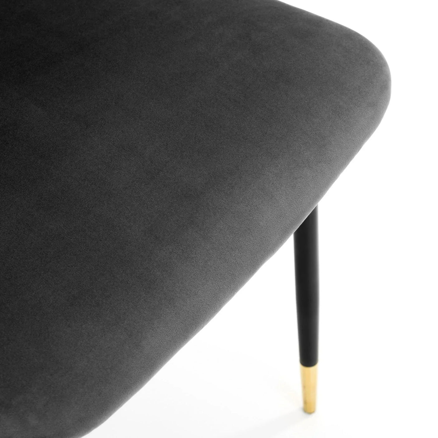 Grey chair seat detail with soft upholstery and black leg featuring a gold tip