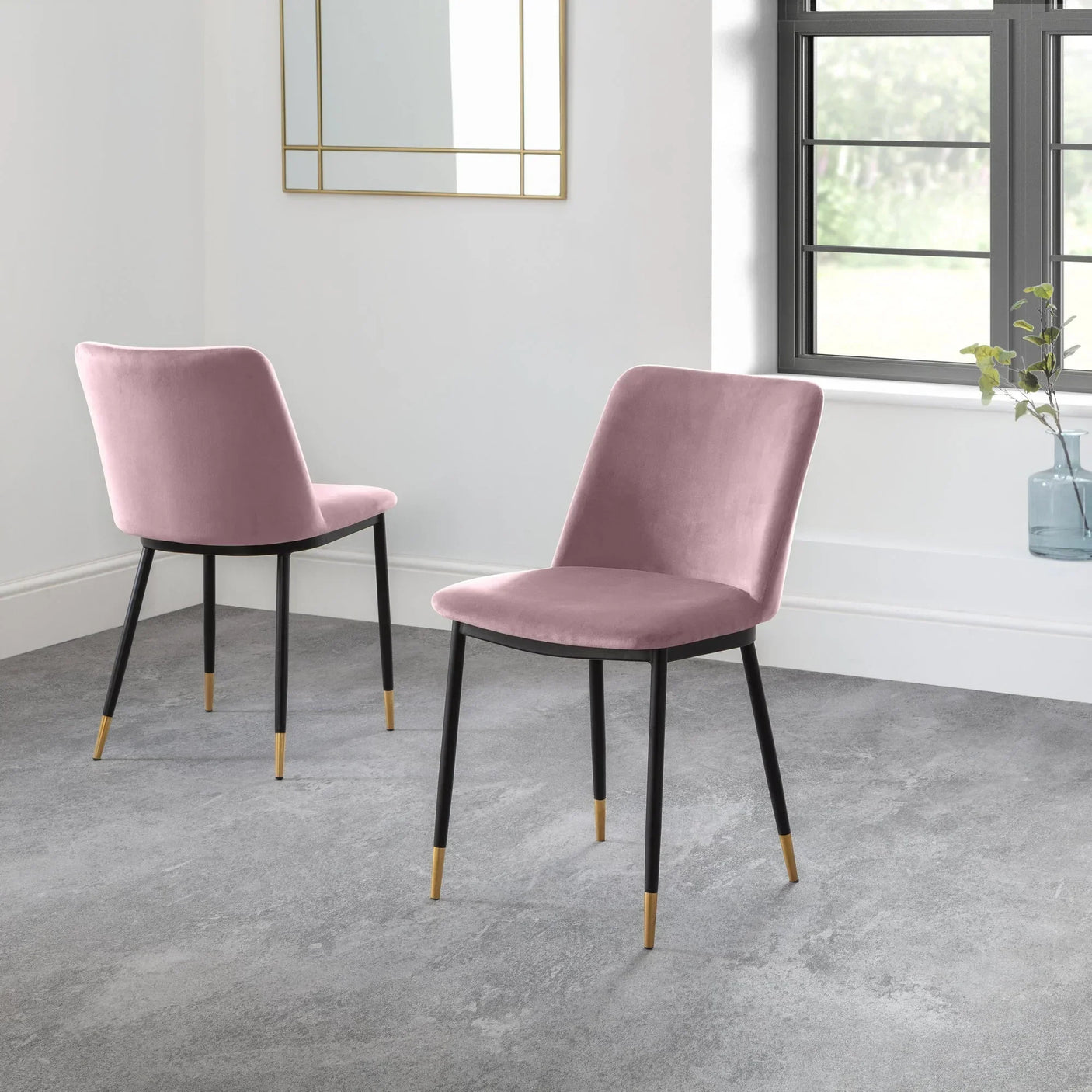 Pink dining chairs with black legs and gold tips in a modern room with grey flooring