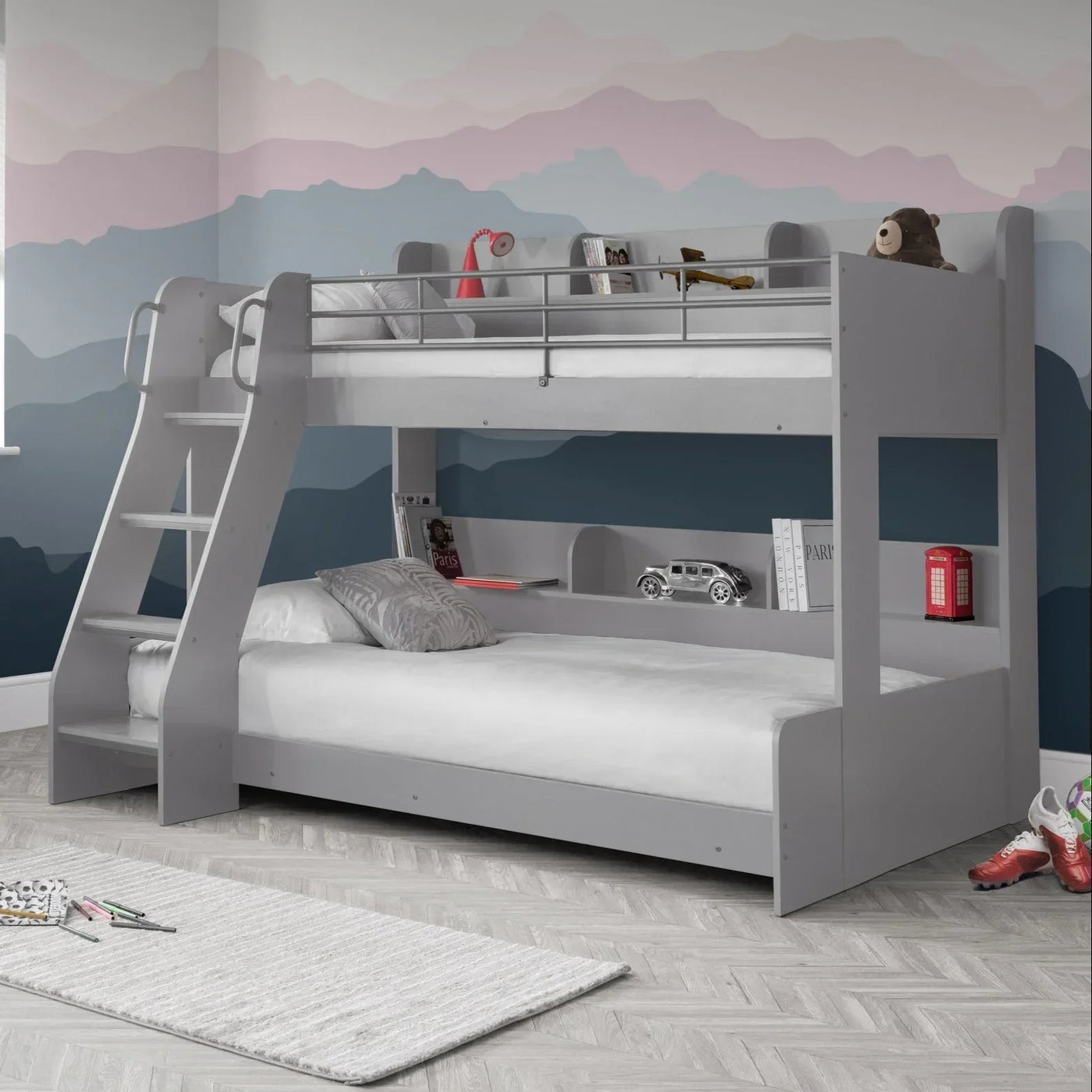 Light grey triple sleeper bunk bed with ladder, lower shelf, and children’s room decor