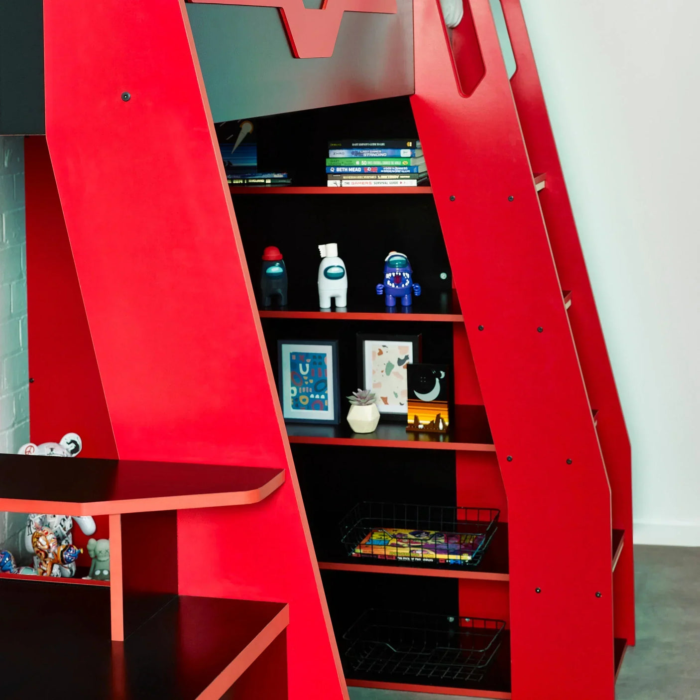 Red kids bunk bed with built-in shelving holding books, toys and framed prints