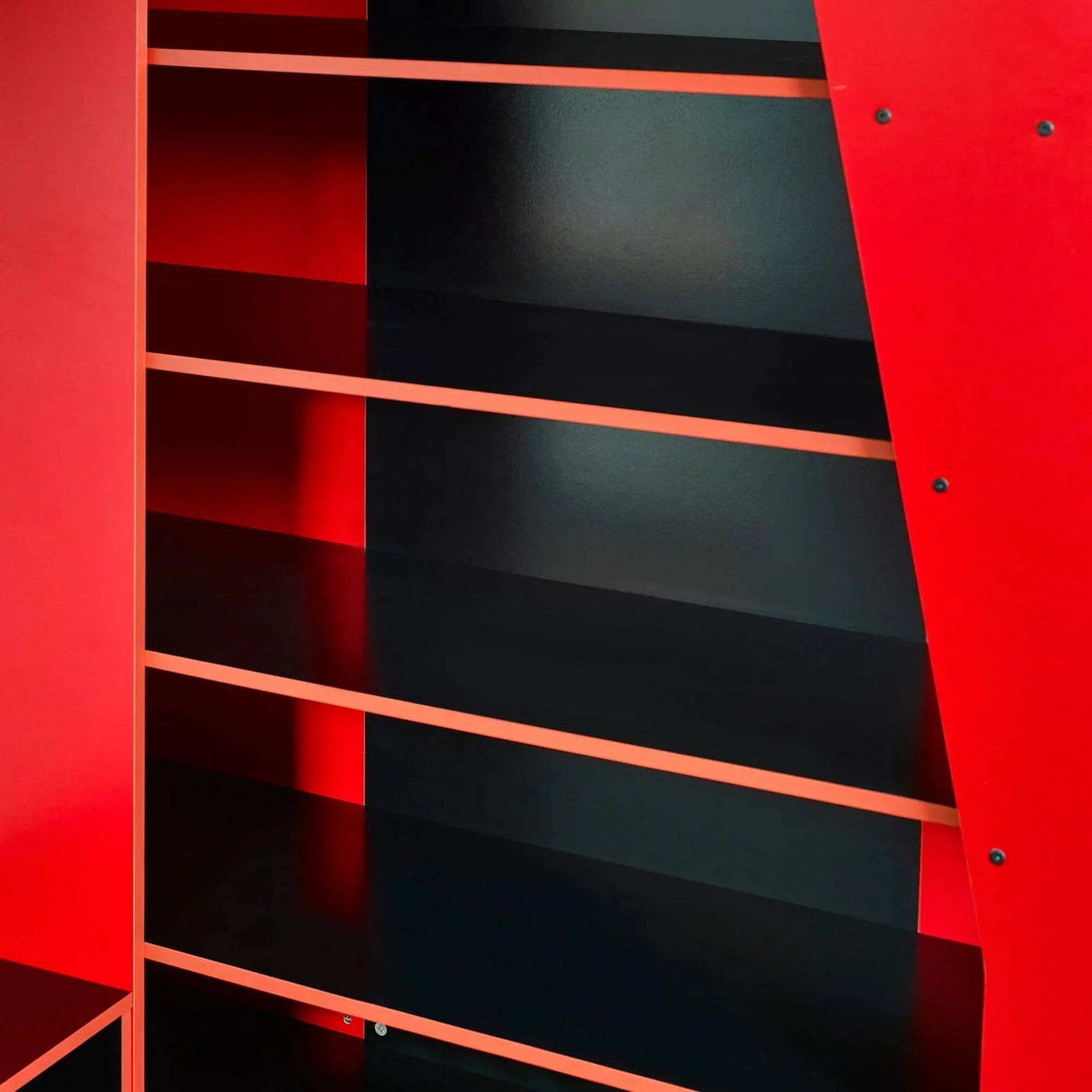 Red and black shelving unit with multiple wide shelves and angled side panel