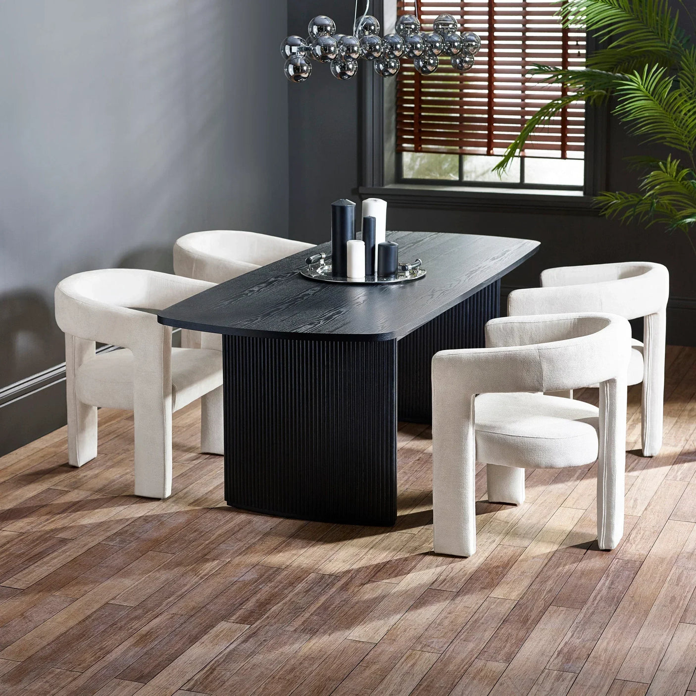 Black wood dining table with four cream velvet dining chairs in a modern dining room