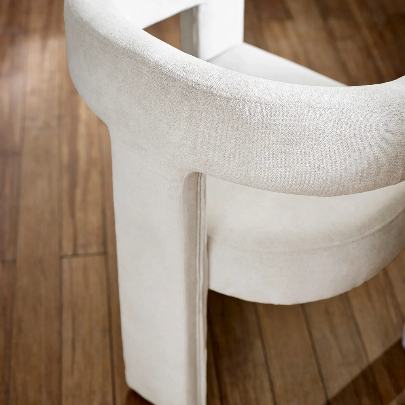 Curved cream upholstered accent chair with modern design on wooden floor