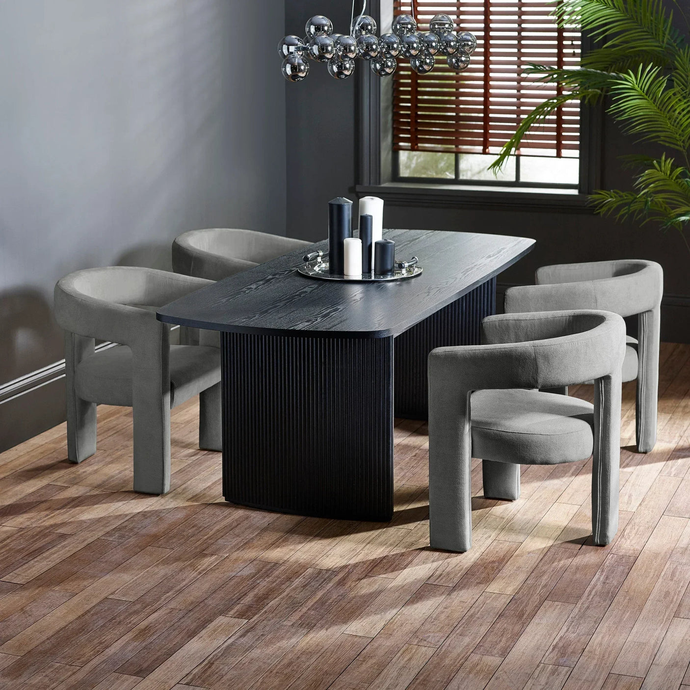 Modern black dining table with four grey fabric chairs in contemporary dining room setting