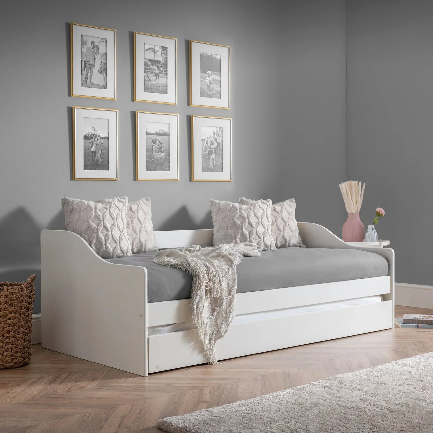 White single daybed with grey mattress, decorative pillows, and throw in modern room setting