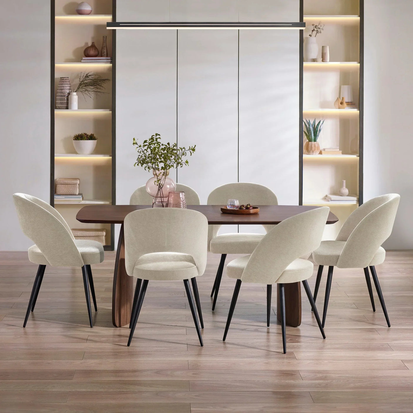 Rectangular wood dining table with six cream fabric dining chairs and black legs in modern room