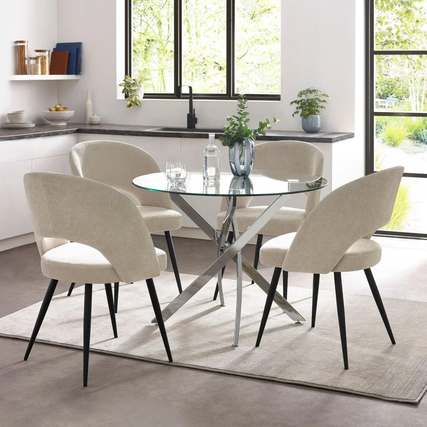 Glass dining table with chrome legs and four beige velvet dining chairs in modern kitchen