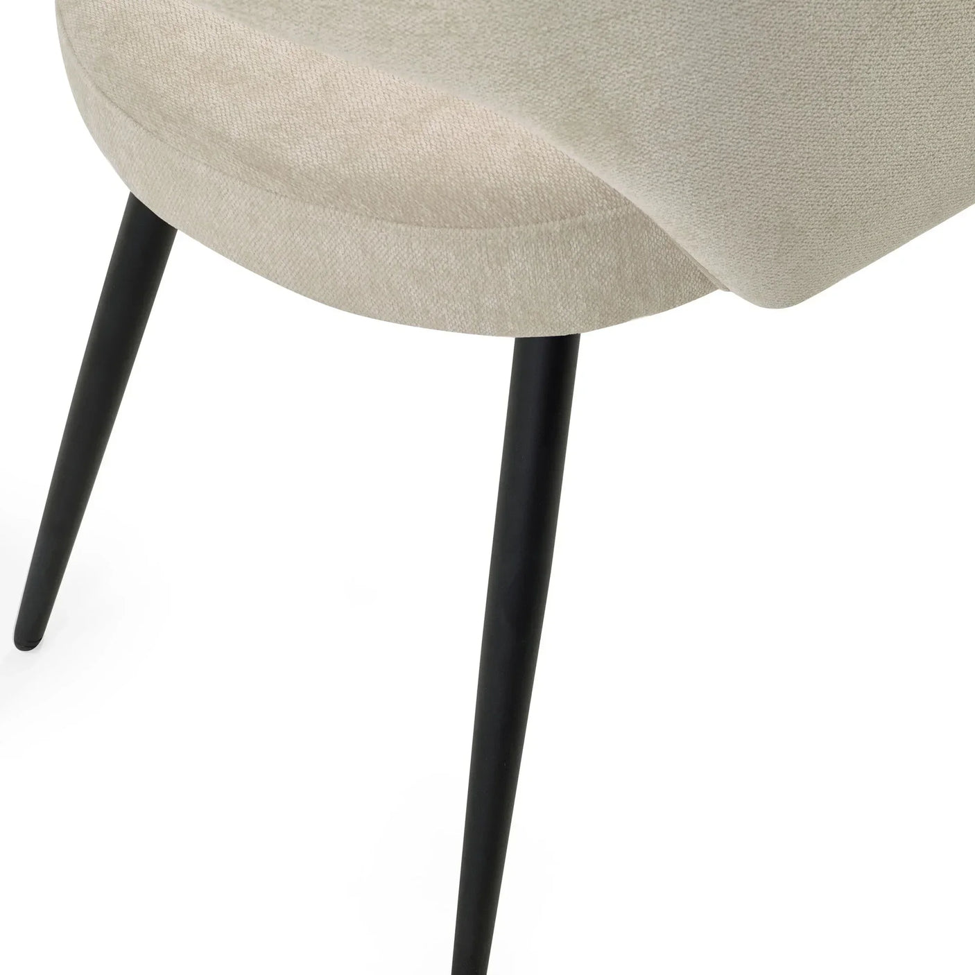 Beige fabric dining chair seat with black tapered metal legs, closeup on side angle