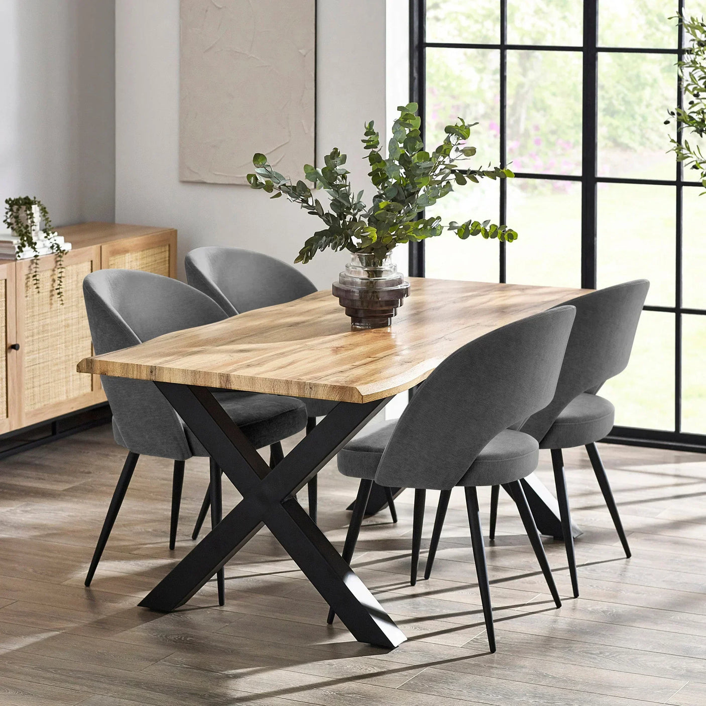 Wood dining table with black metal legs and four grey velvet chairs in modern dining room