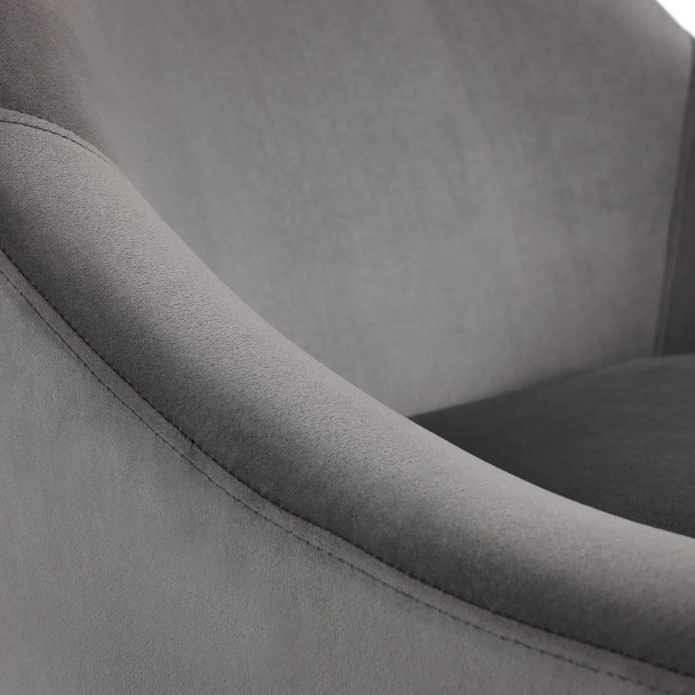 Closeup of grey velvet armchair showing curved arm and stitched upholstery