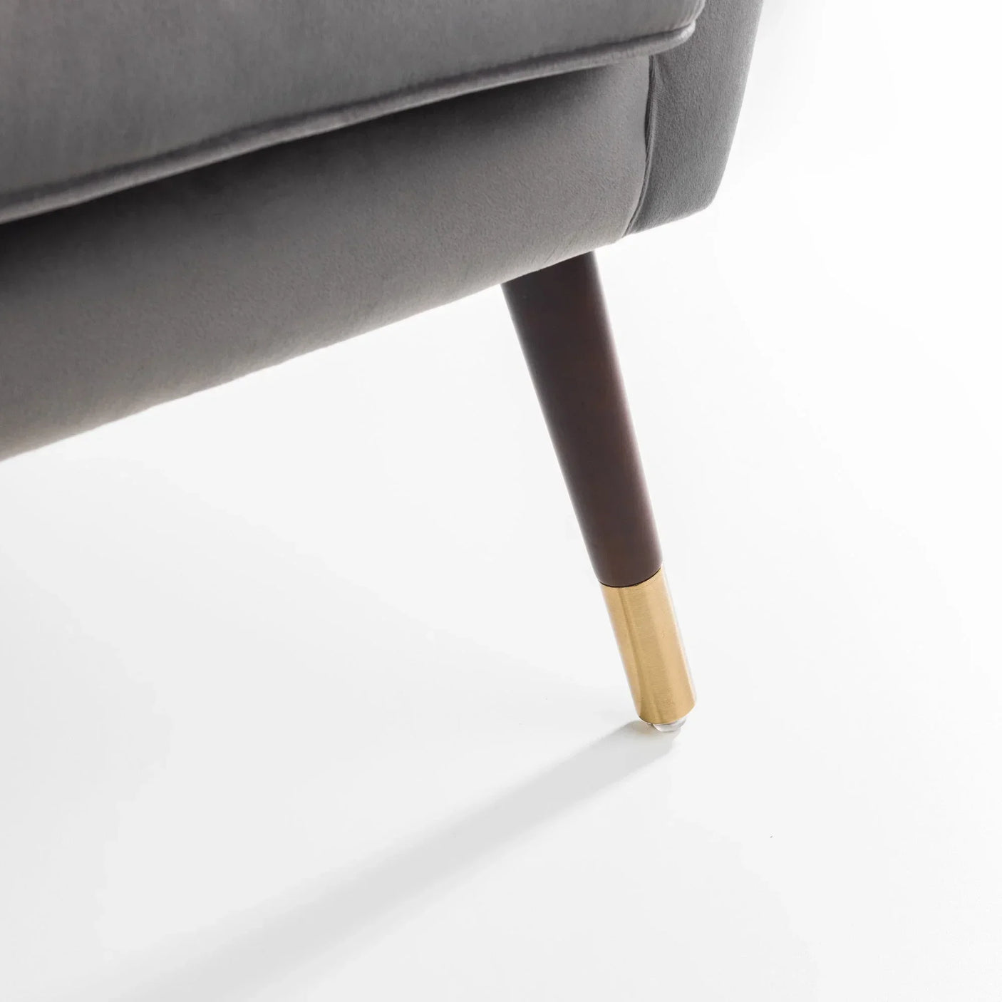 Grey sofa leg with gold metal tip on white background