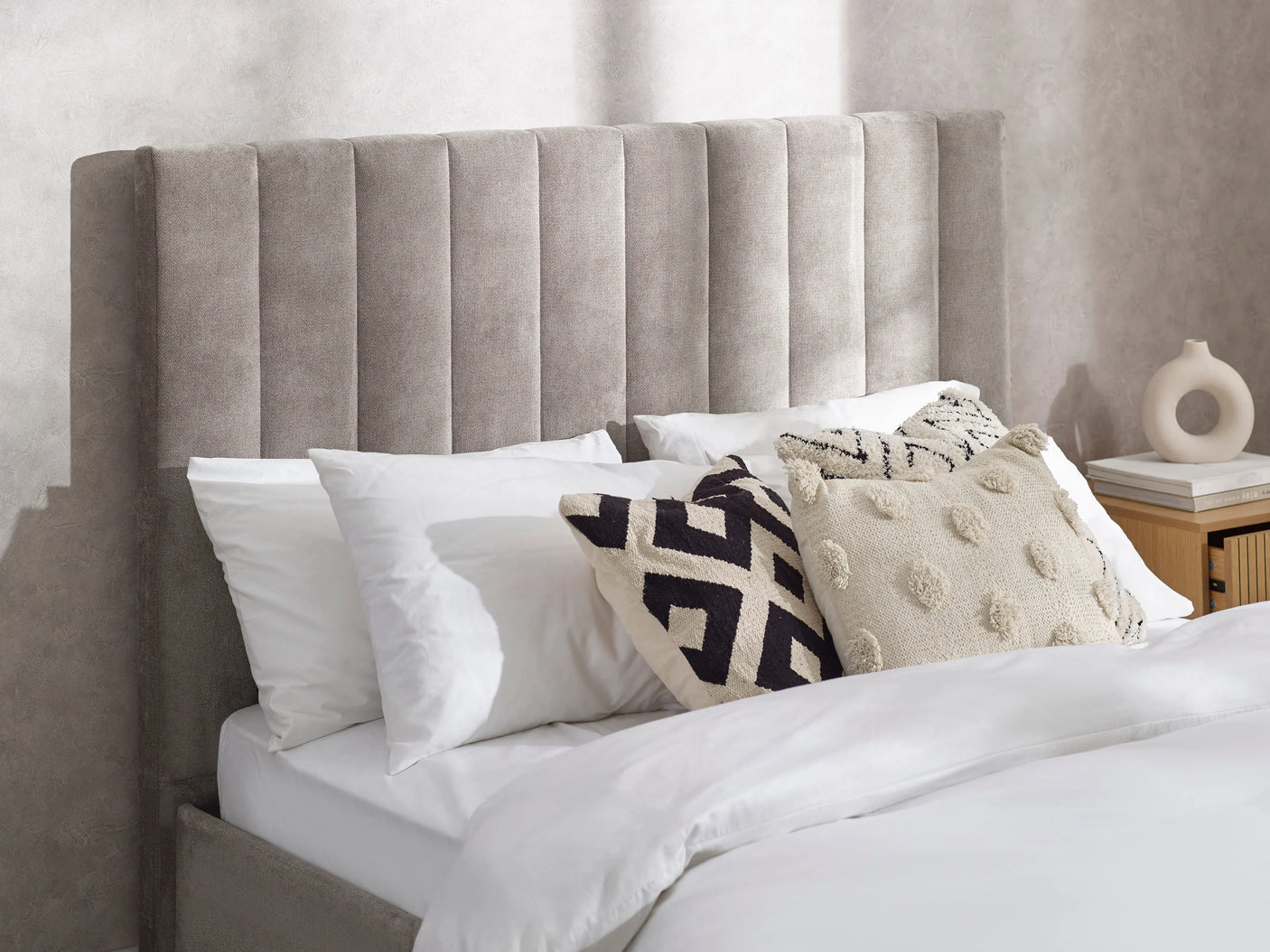 Grey upholstered double bed with vertical panel headboard and decorative cushions