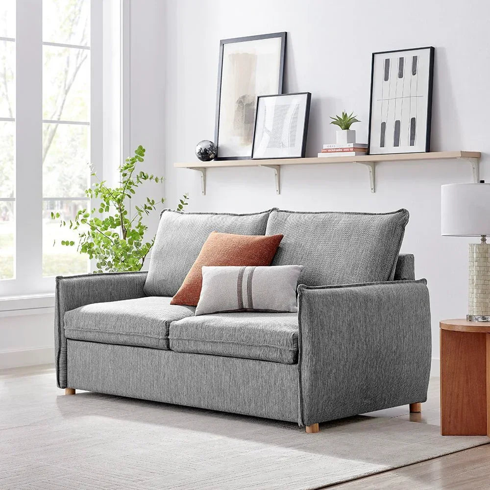 Grey fabric sofa with two seat cushions and accent pillows in bright living room setting