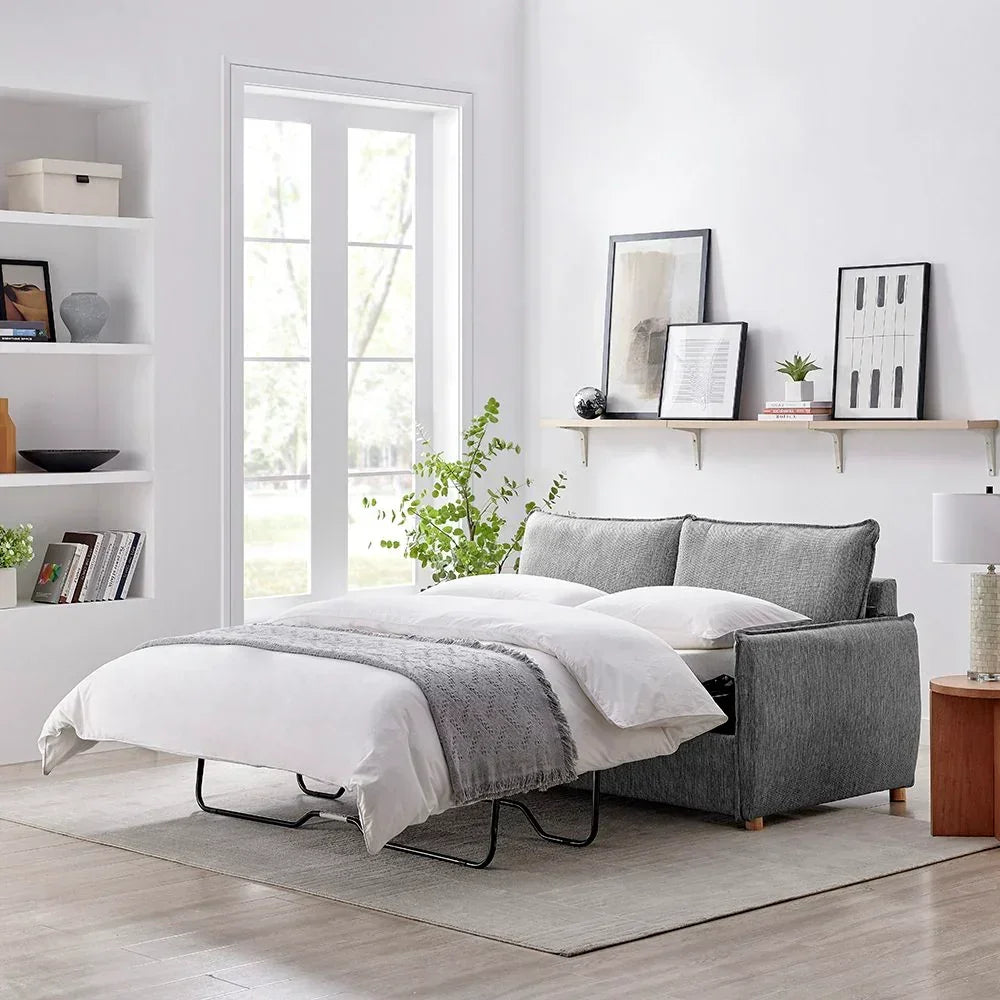 Grey fabric sofa bed extended in bright living room with white bedding and throw