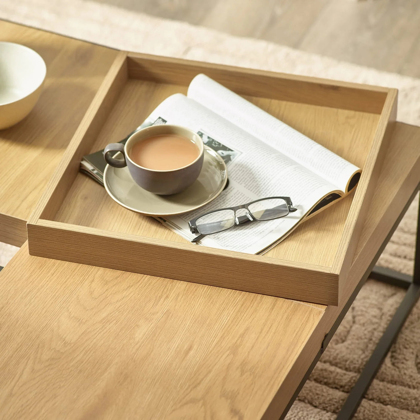 Oak coffee table with tray top, cup of tea, open magazine and reading glasses
