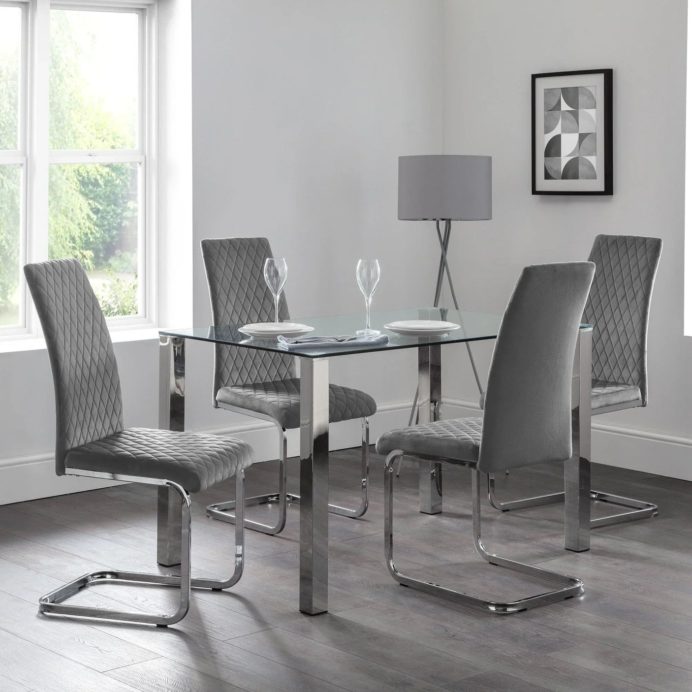 Glass Enzo dining table with chrome legs and four grey velvet cantilever chairs in modern room