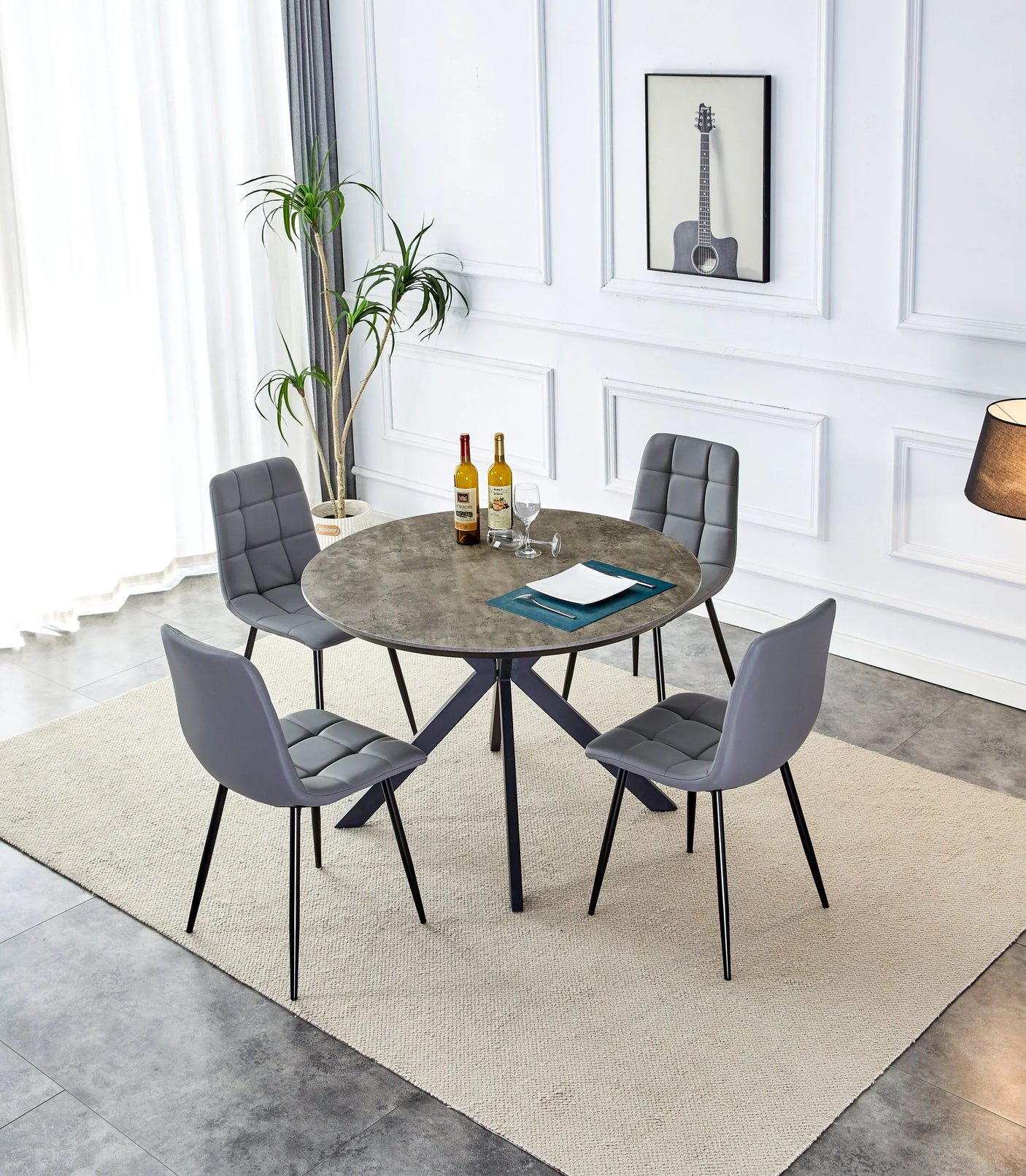 Round grey dining table with four grey PU chairs on a rug in modern dining room