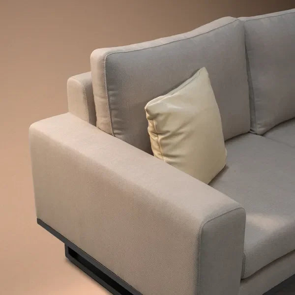Beige fabric corner sofa with wide armrest and cream cushion, close-up view