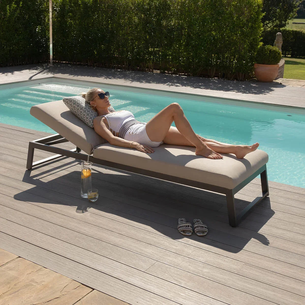 Aluminium outdoor sun lounger with cushion by pool on garden decking