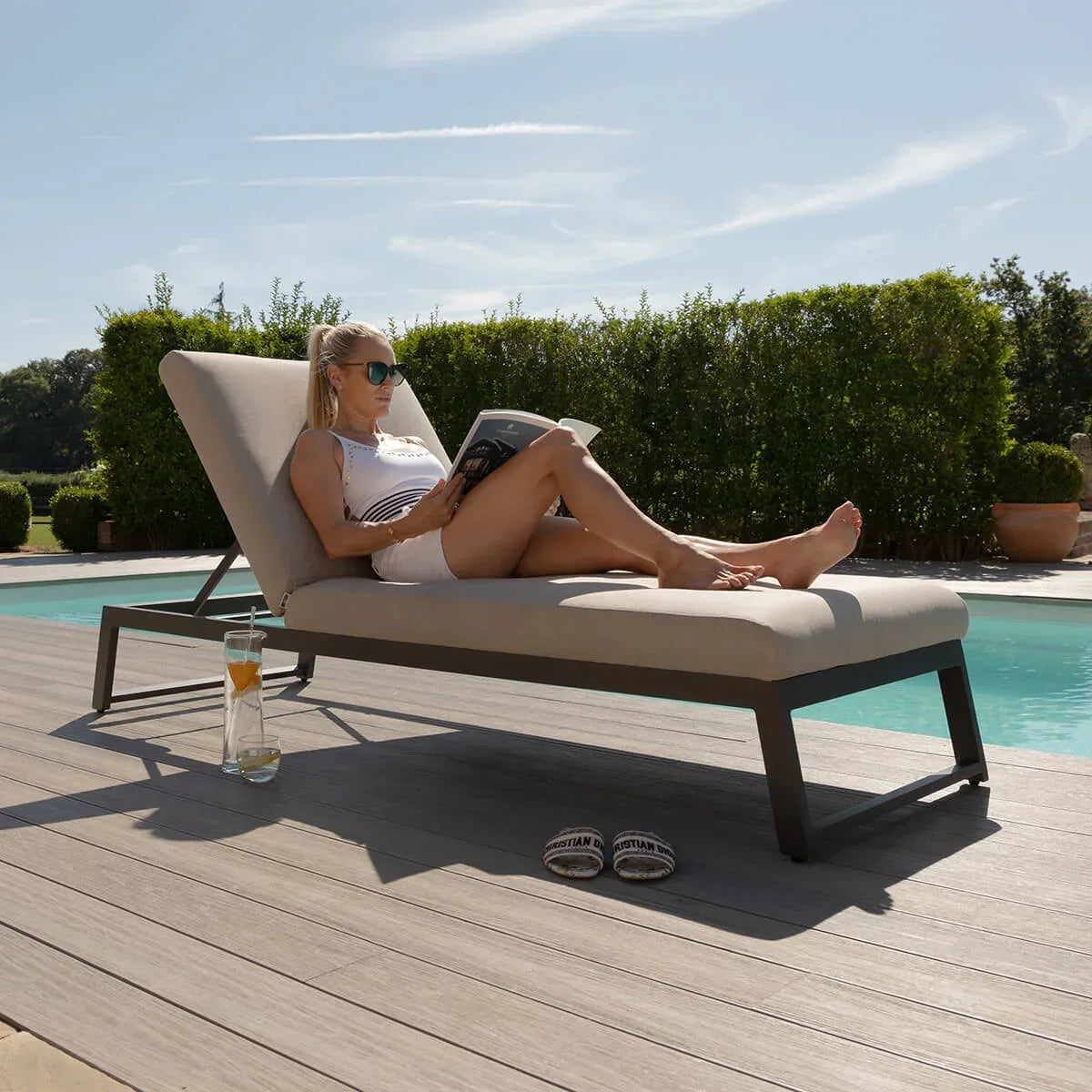 aluminium outdoor sun lounger with beige cushion beside pool on decking
